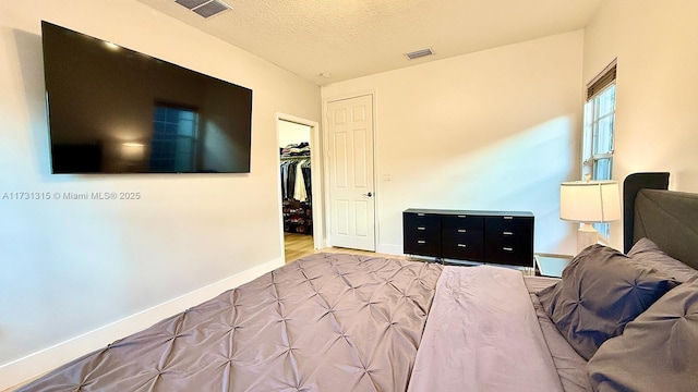 bedroom featuring baseboards, a closet, visible vents, and a textured ceiling