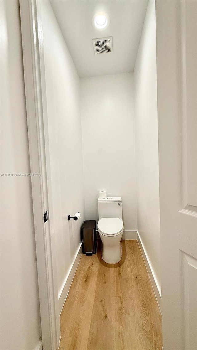 bathroom featuring toilet, wood finished floors, visible vents, and baseboards