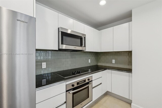 kitchen featuring tasteful backsplash, appliances with stainless steel finishes, light tile patterned floors, and white cabinets