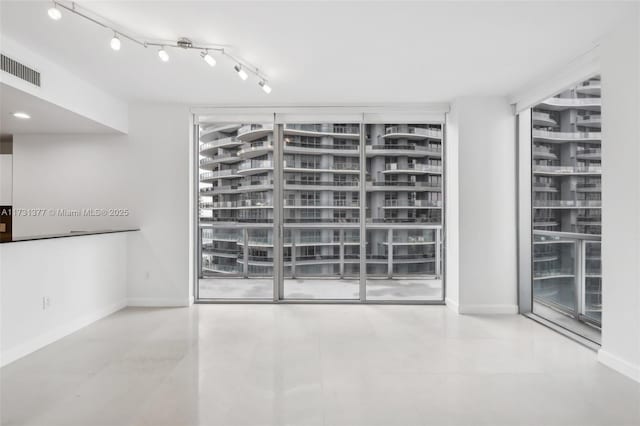 empty room featuring track lighting and floor to ceiling windows