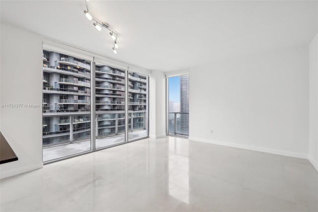 unfurnished room featuring track lighting and floor to ceiling windows