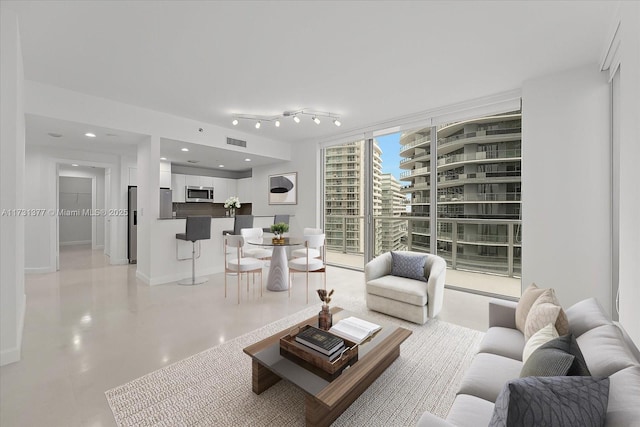 living room featuring expansive windows, concrete flooring, baseboards, and visible vents