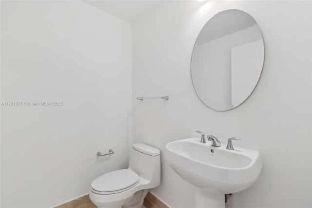 bathroom featuring toilet, baseboards, and a sink