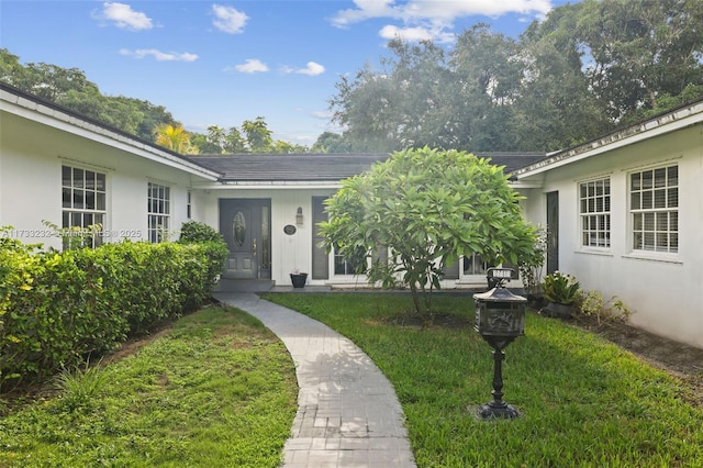 doorway to property with a lawn