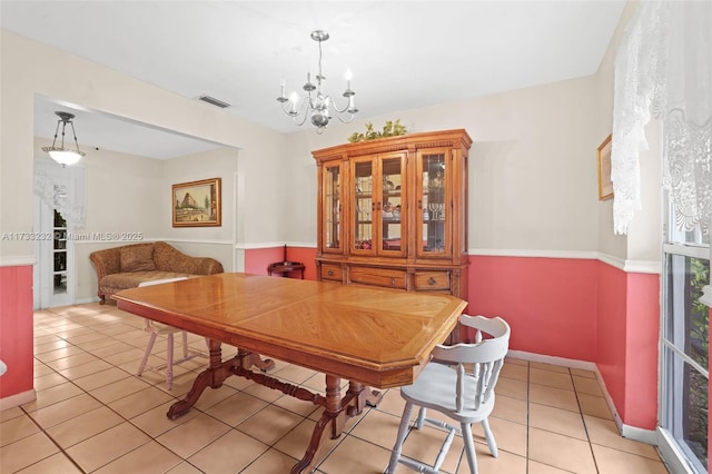 tiled dining room with an inviting chandelier