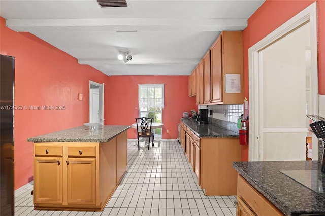 kitchen with tasteful backsplash, a center island, beamed ceiling, and light tile patterned flooring