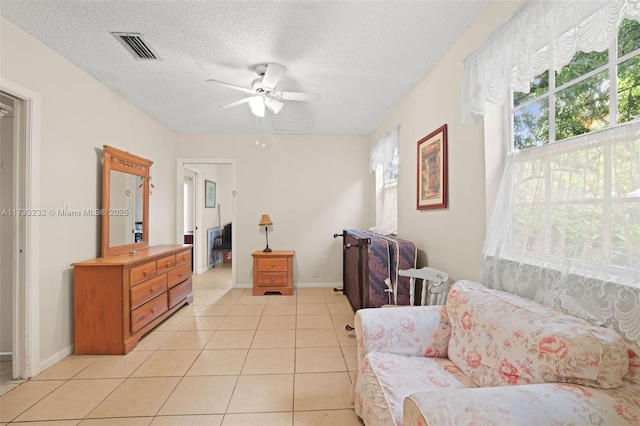 living area featuring ceiling fan, a textured ceiling, and light tile patterned floors