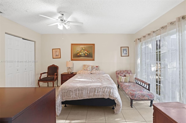 bedroom featuring ceiling fan, a textured ceiling, a closet, and light tile patterned floors