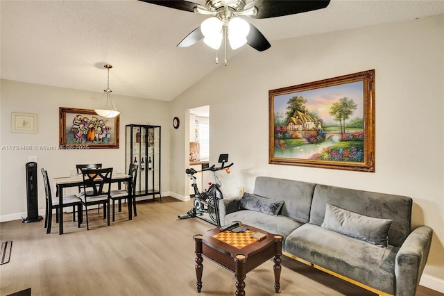 living room featuring vaulted ceiling, ceiling fan, and light hardwood / wood-style flooring