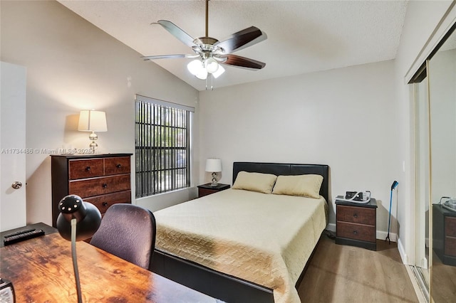 bedroom with lofted ceiling, ceiling fan, wood-type flooring, a textured ceiling, and a closet