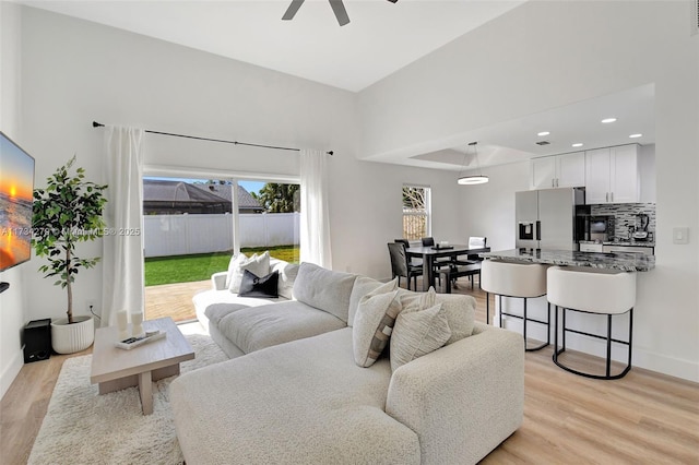 living room with light hardwood / wood-style flooring and ceiling fan