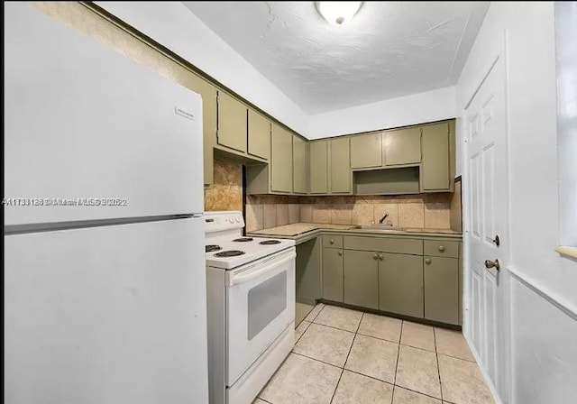 kitchen with tasteful backsplash, light tile patterned flooring, green cabinets, and white appliances