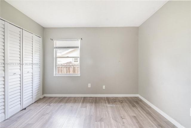 unfurnished bedroom with a closet, light wood-style flooring, and baseboards