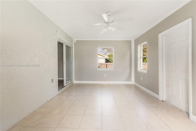 spare room with ceiling fan, ornamental molding, baseboards, and light tile patterned flooring