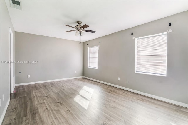 empty room featuring visible vents, ceiling fan, baseboards, and wood finished floors