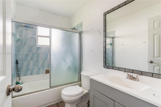 full bathroom with toilet, shower / bath combination with glass door, and vanity