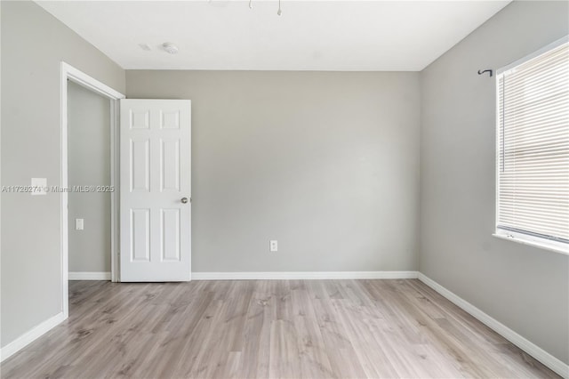 unfurnished room featuring a healthy amount of sunlight, light wood finished floors, and baseboards