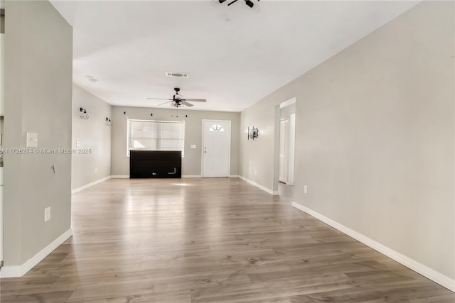 unfurnished living room featuring visible vents, ceiling fan, baseboards, and wood finished floors