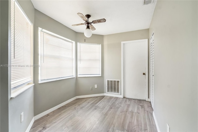 unfurnished room with ceiling fan, wood finished floors, visible vents, and baseboards