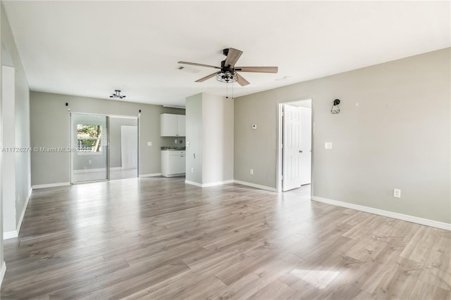 spare room with light wood finished floors, washer / dryer, visible vents, baseboards, and a ceiling fan