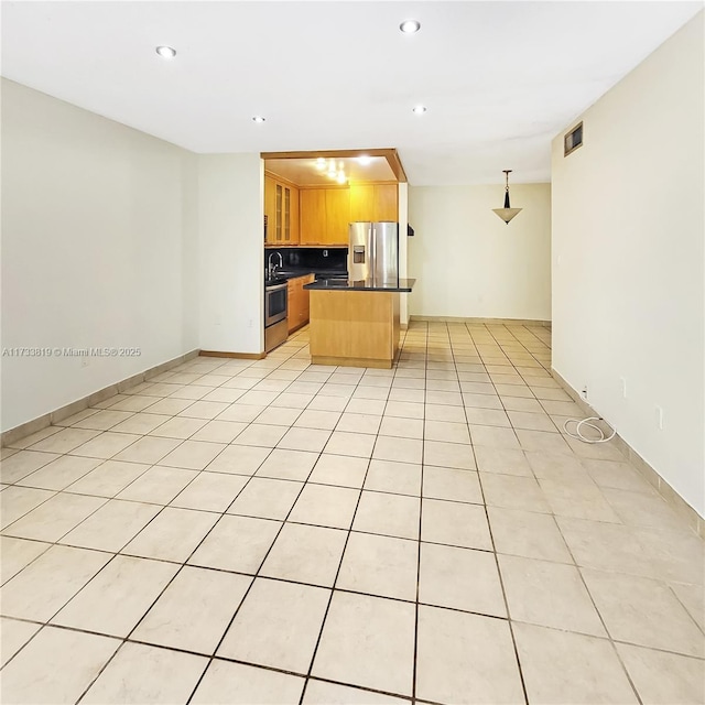 kitchen with pendant lighting, light tile patterned floors, appliances with stainless steel finishes, tasteful backsplash, and a kitchen island