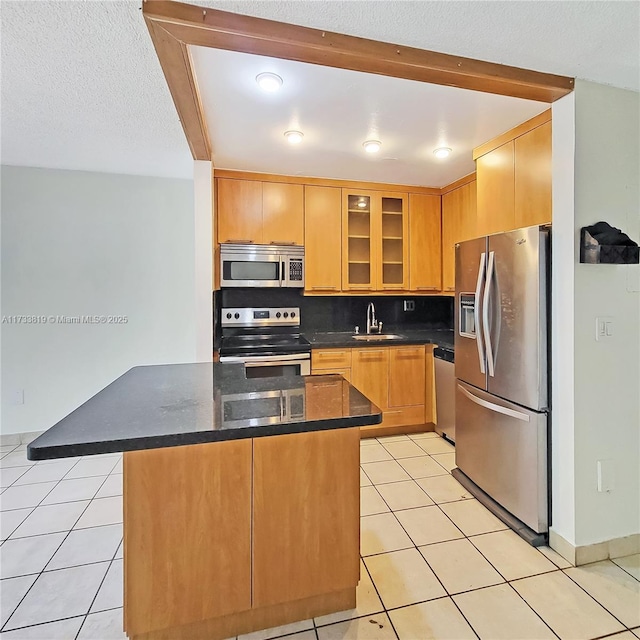 kitchen featuring sink, light tile patterned floors, a kitchen island, and appliances with stainless steel finishes