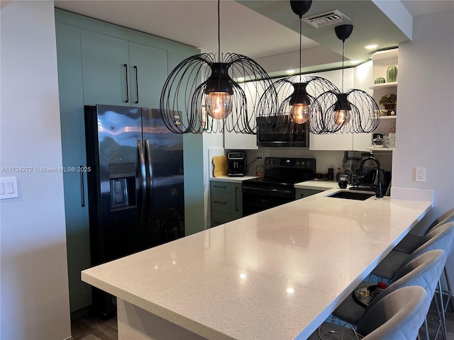 kitchen featuring a breakfast bar, sink, black electric range oven, hanging light fixtures, and kitchen peninsula