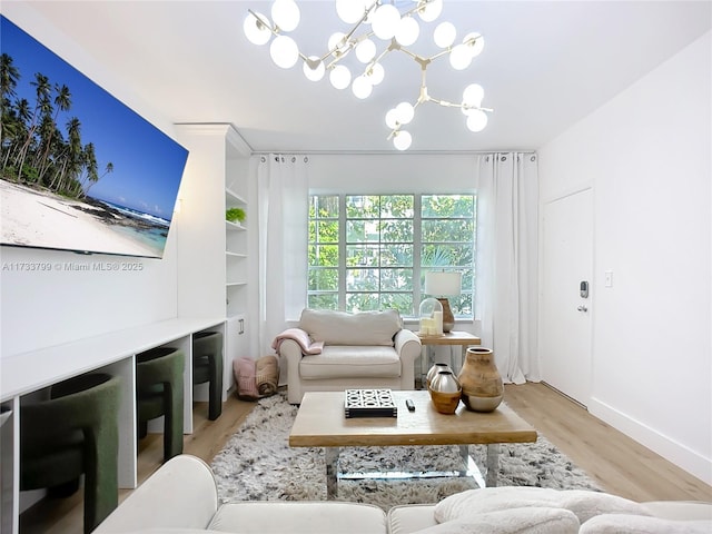 living room featuring built in features, a chandelier, and light hardwood / wood-style flooring