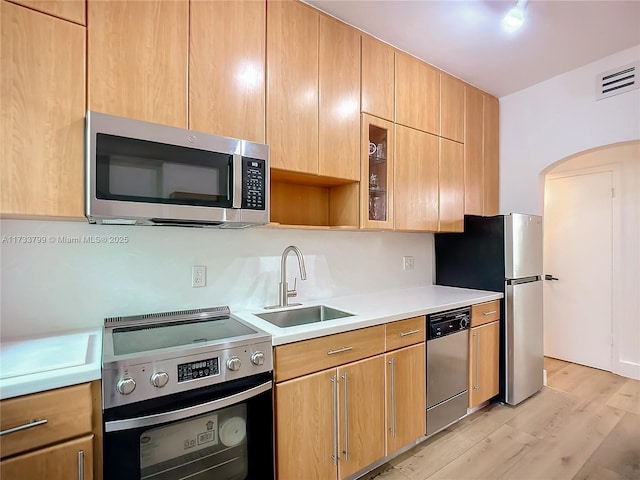 kitchen with stainless steel appliances, sink, and light hardwood / wood-style flooring