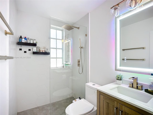 bathroom with tiled shower, vanity, and toilet