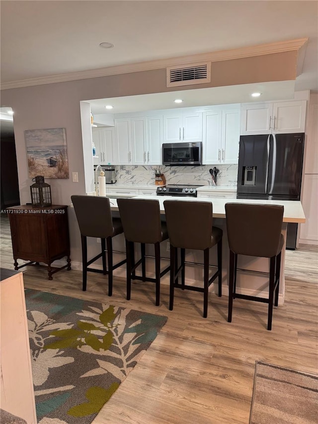 kitchen featuring white cabinetry, tasteful backsplash, a breakfast bar, and appliances with stainless steel finishes