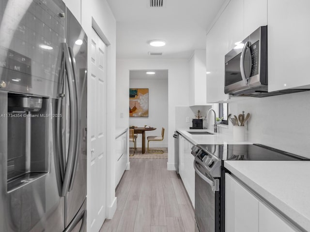 kitchen with white cabinetry, sink, and stainless steel appliances