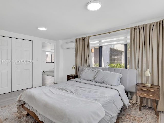 bedroom featuring a wall mounted AC and light hardwood / wood-style flooring