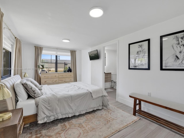 bedroom with connected bathroom and light wood-type flooring