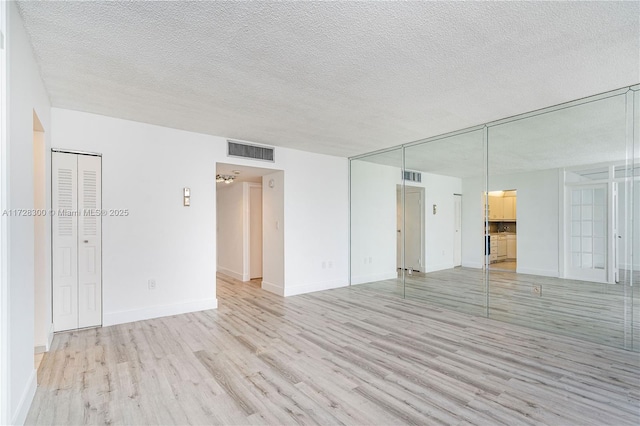 empty room featuring a textured ceiling and light wood-type flooring