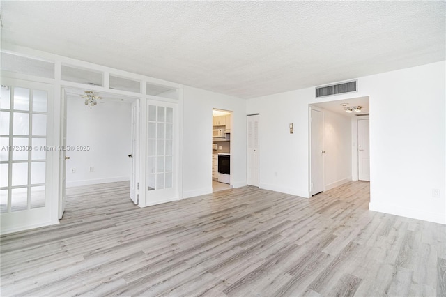 empty room with light hardwood / wood-style floors and a textured ceiling