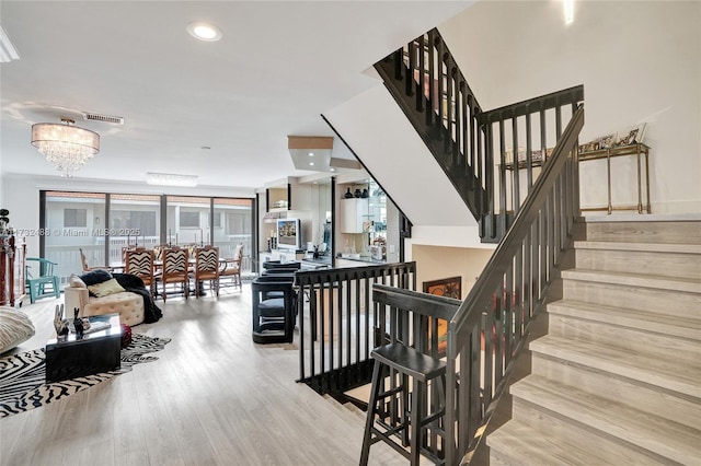 stairway with wood-type flooring and a chandelier