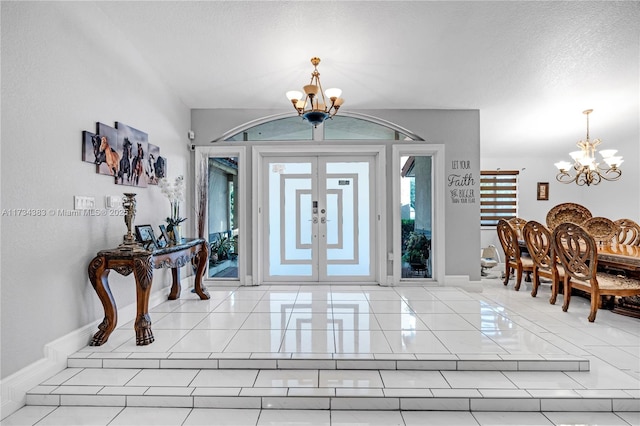 entryway with baseboards, a chandelier, a textured ceiling, and french doors