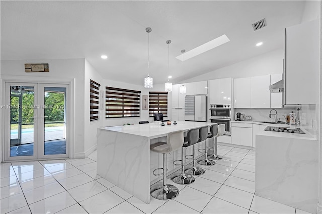 kitchen with visible vents, a kitchen island, appliances with stainless steel finishes, white cabinetry, and pendant lighting