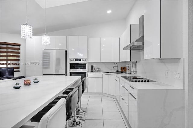 kitchen featuring white cabinets, modern cabinets, decorative light fixtures, freestanding refrigerator, and wall chimney range hood