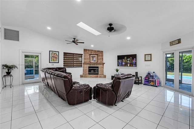 living room with visible vents, a stone fireplace, light tile patterned flooring, and a ceiling fan