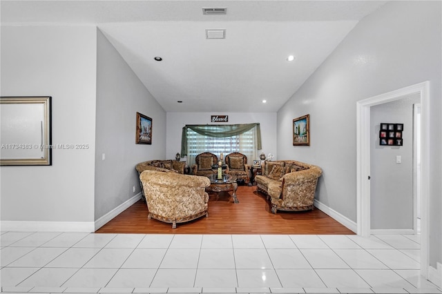 living area with light tile patterned floors, vaulted ceiling, and visible vents