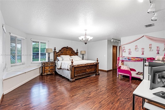 bedroom with a chandelier, a textured ceiling, visible vents, dark wood finished floors, and track lighting