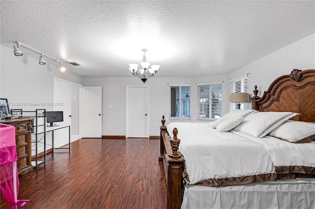 bedroom featuring baseboards, visible vents, dark wood finished floors, a textured ceiling, and a chandelier