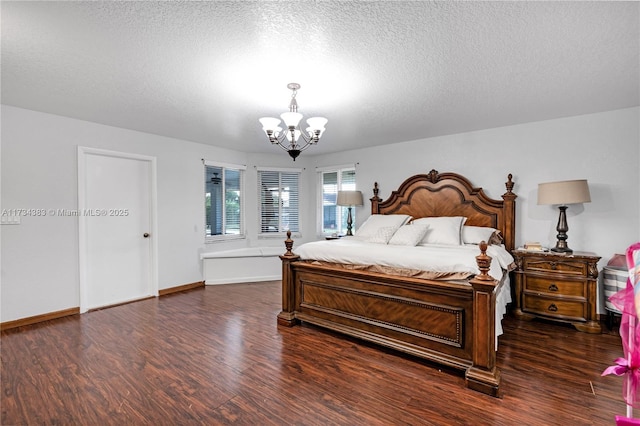 bedroom with a notable chandelier, dark wood finished floors, and a textured ceiling