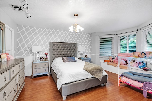 bedroom featuring wallpapered walls, an accent wall, and wood finished floors