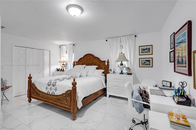 bedroom with a closet, marble finish floor, and a textured ceiling