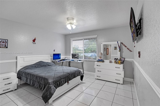 bedroom with a textured ceiling, a textured wall, light tile patterned flooring, and baseboards