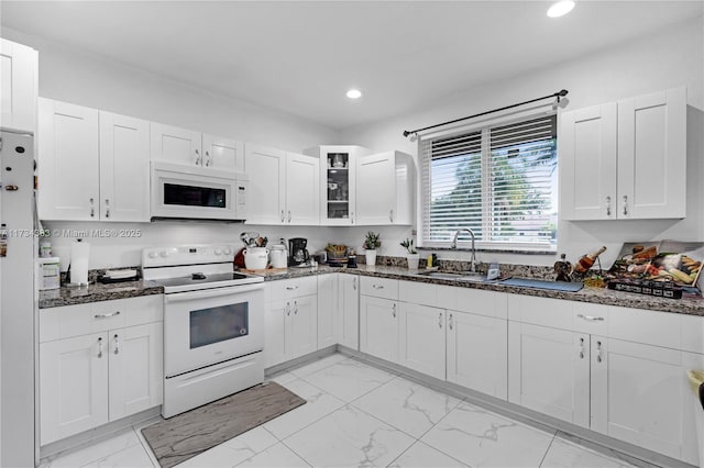 kitchen featuring white appliances, white cabinetry, glass insert cabinets, and a sink