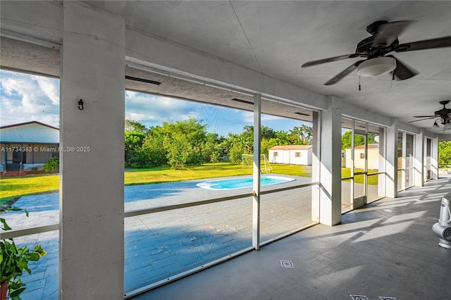 unfurnished sunroom featuring a ceiling fan